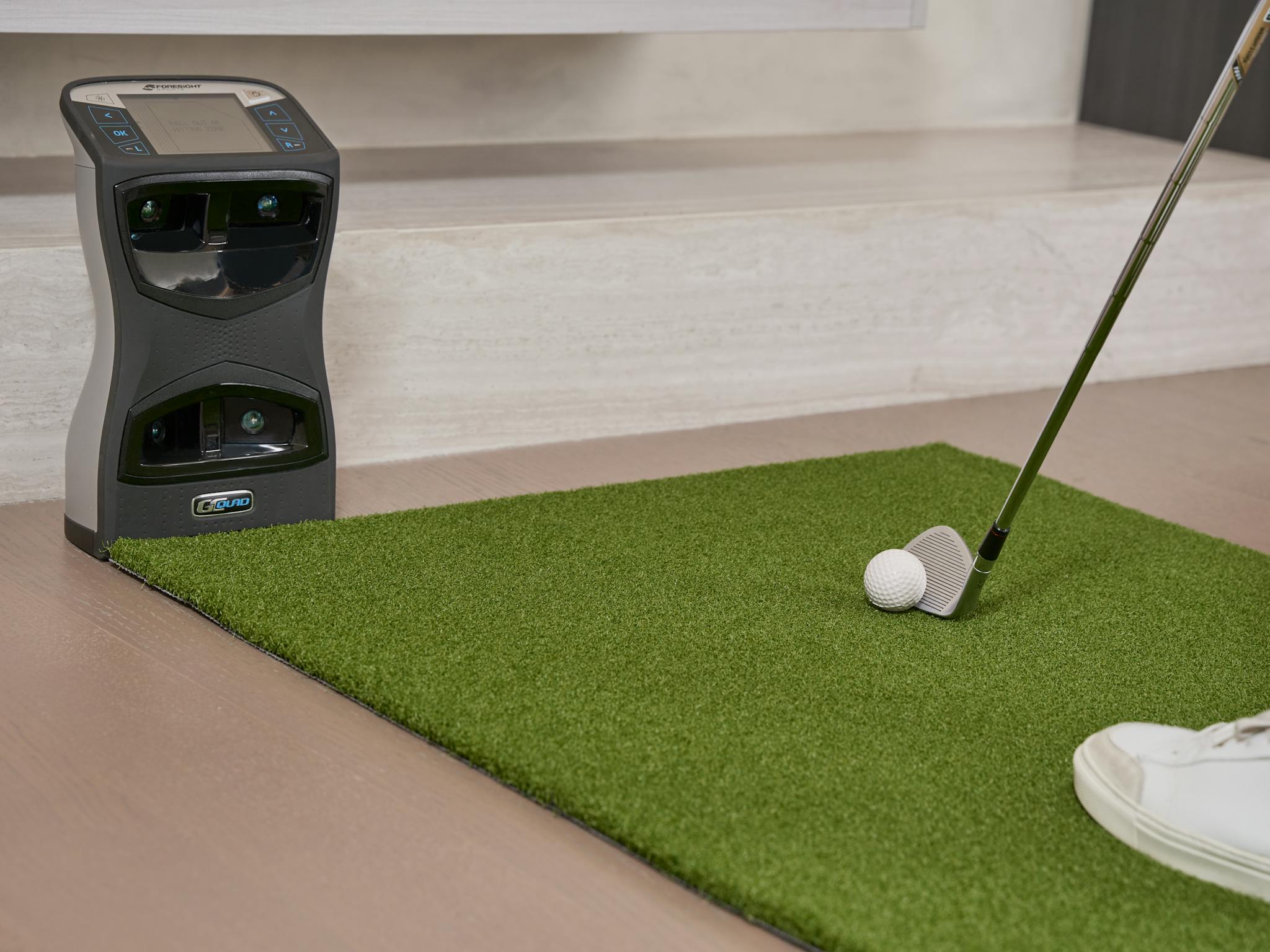 Golf putting practice on artificial turf with a training aid indoors.